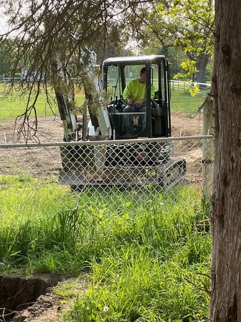 Bobcat excavator working alongside chain-link fence